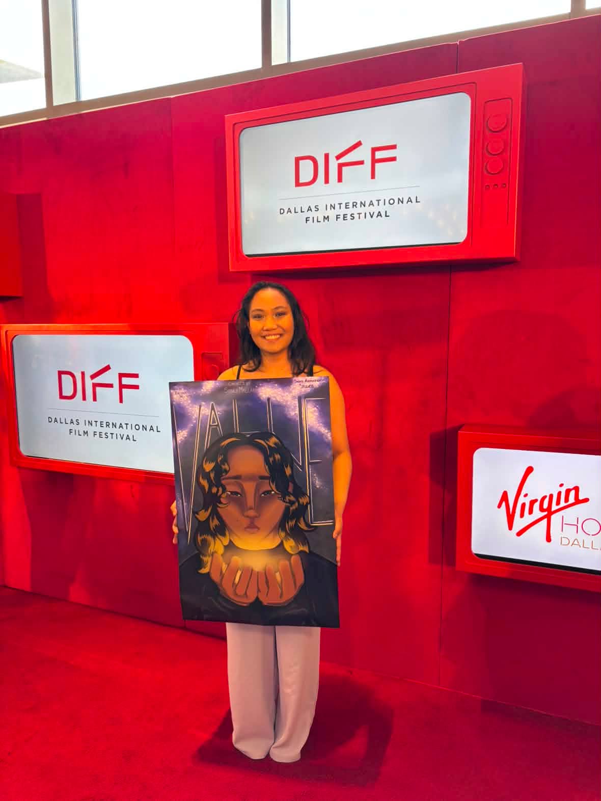 young female holds a sign in front of a red backdrop