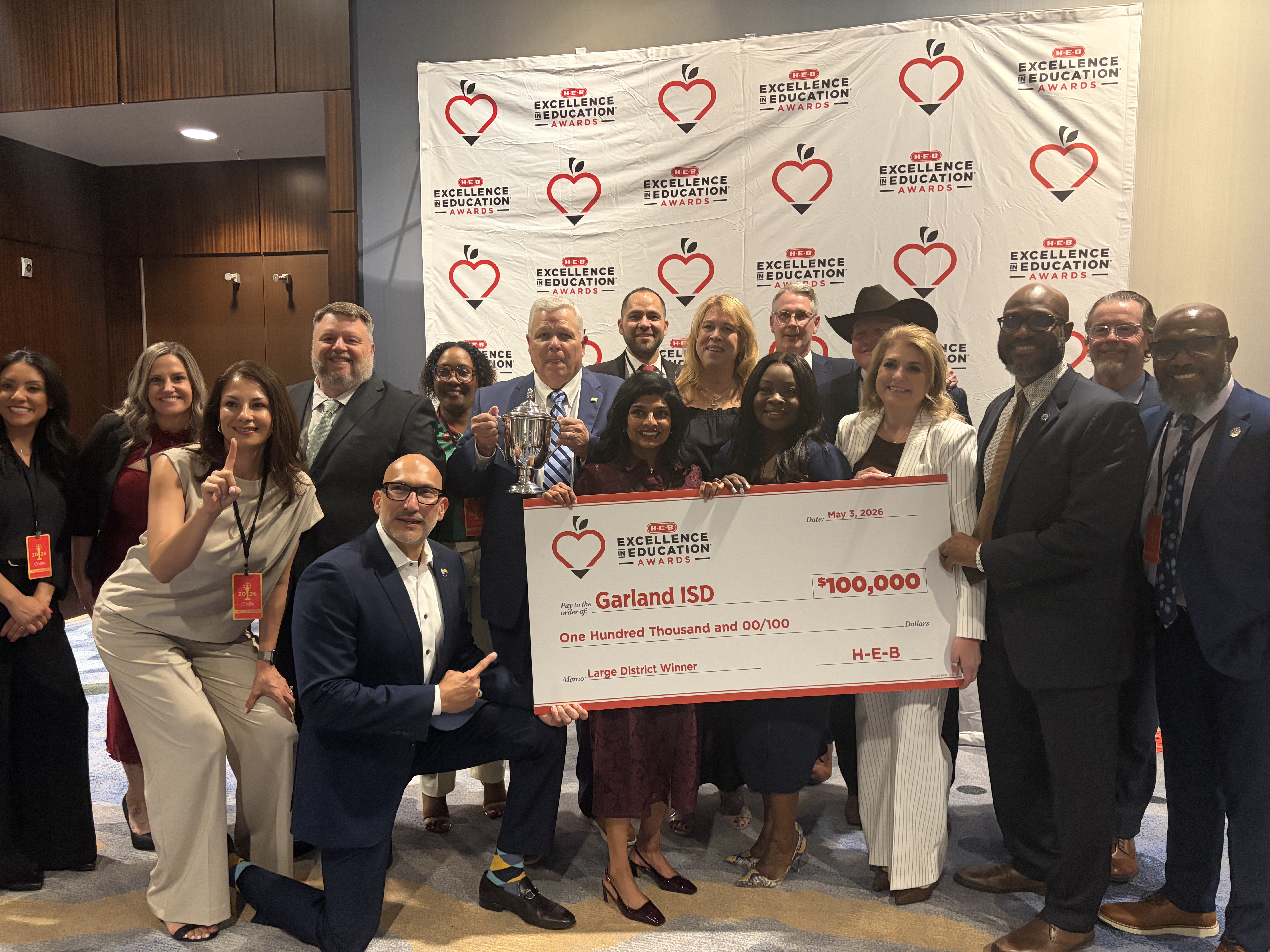 a diverse group of adults stand with a celebratory check