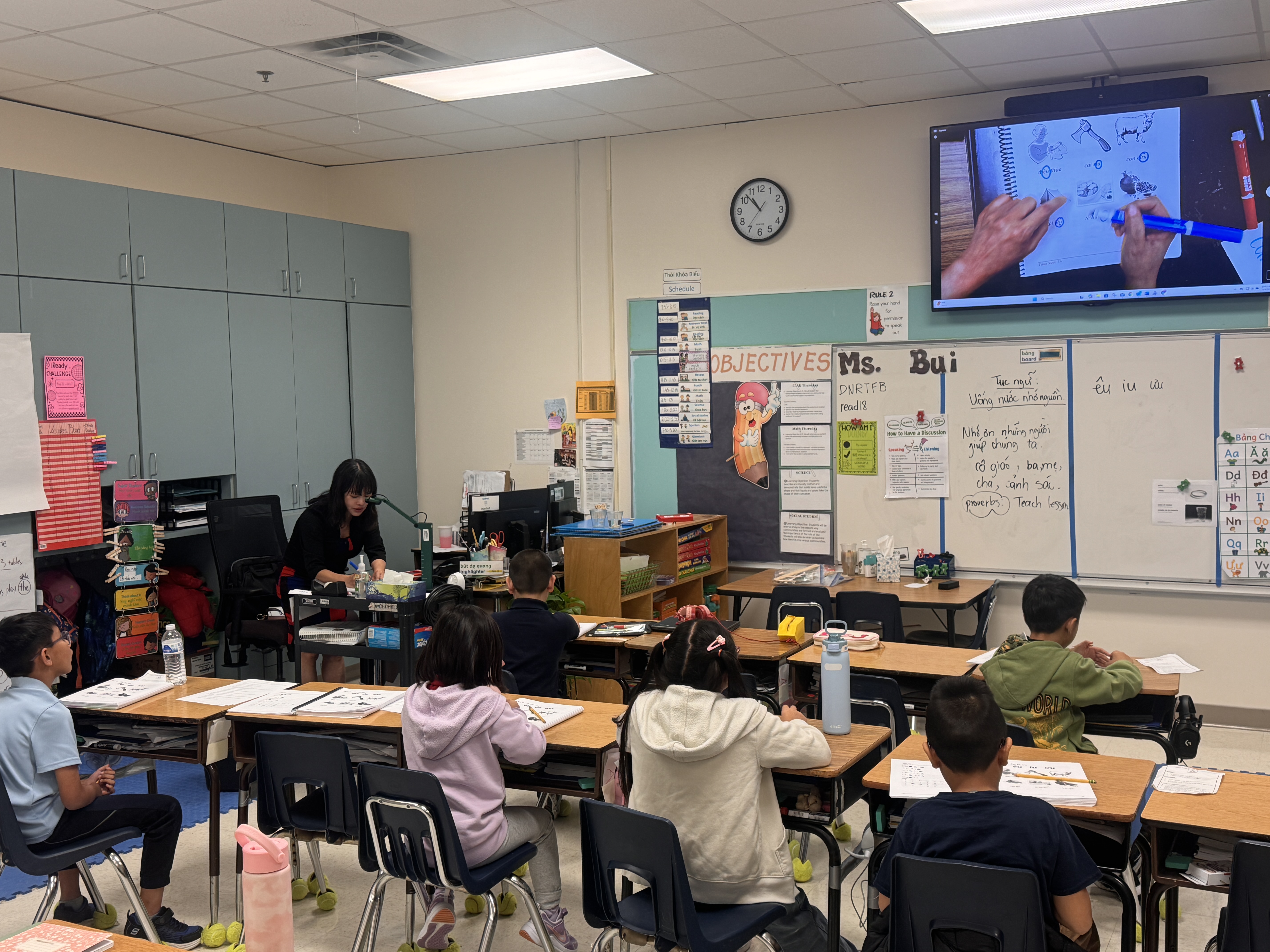 Female teacher works on the overhead projector as her class watches