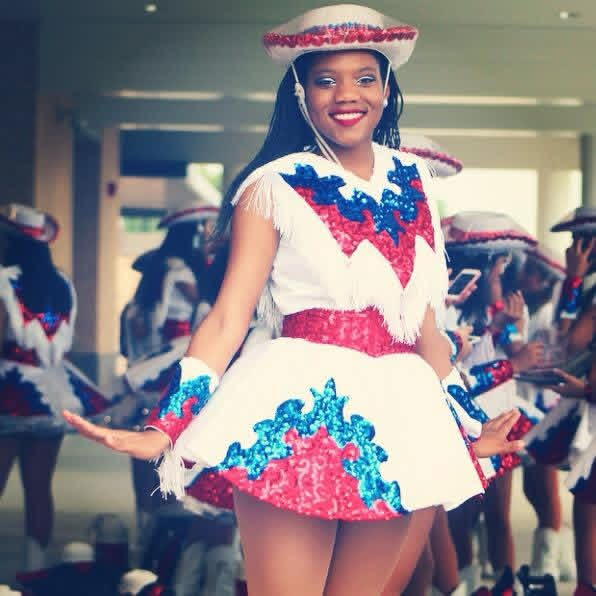 a young female stands in her drill team uniform