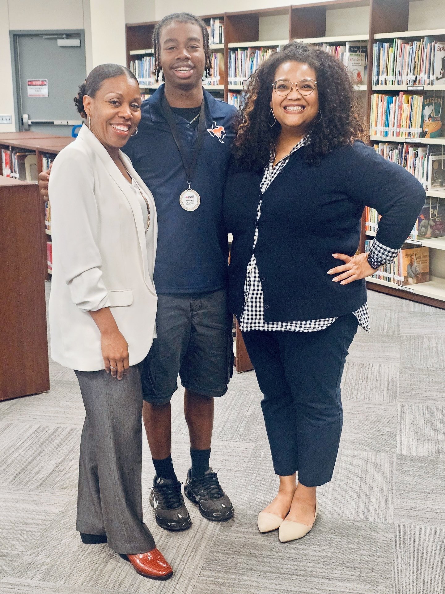 a male student stands with two adult females
