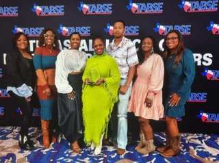 a group of adult stands smiling as the middle female holds an award