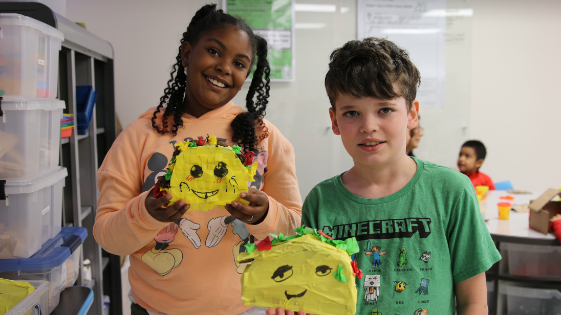 Two students stand holding their piñata projects