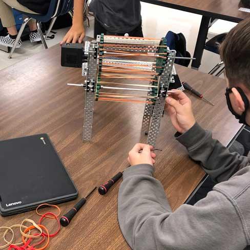 Boy working with metal structure and rubber bands at Jackson Technology Center.