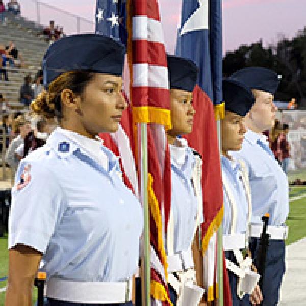 Student cadets hold flags at football game