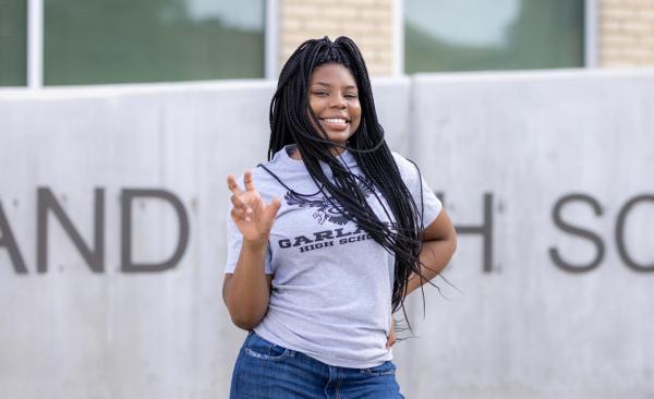 Ivy Veail posing posing in front of GHS while making the school's spirit hand sign.
