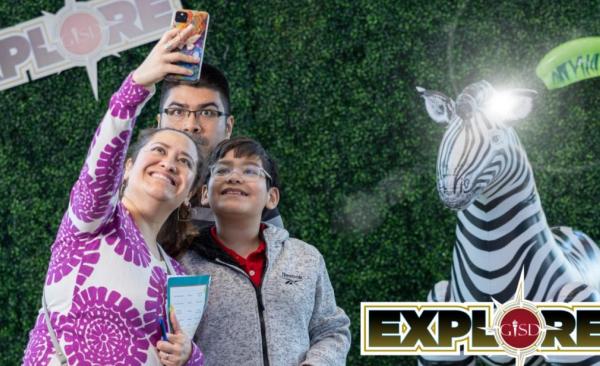 family taking a selfie in front of a safari themed backdrop with a zebra.