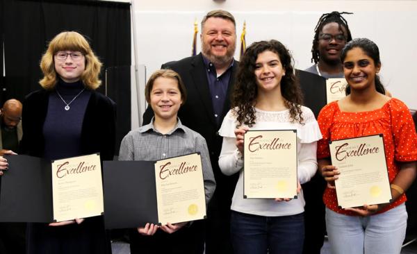 Five students standing with Board President Wes Johhsnon. Each child is holding a certificate