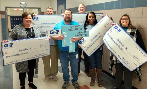 GEF's Lisa Cox posing with several grant winners holding their giant checks.