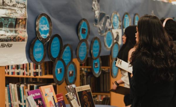 A group of students looks at a display about hip hop in the library.