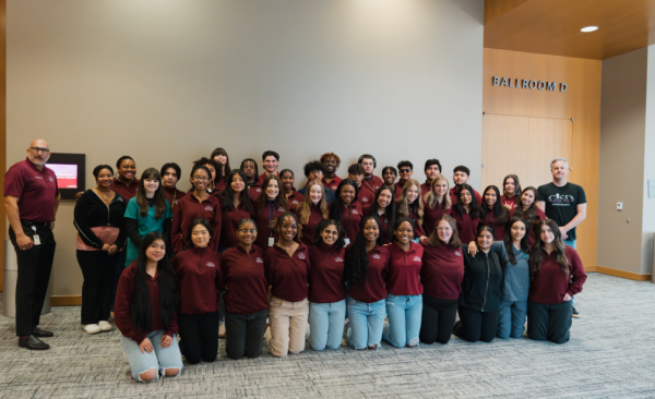 A group of students pose kneeling and standing with the Superintendent.