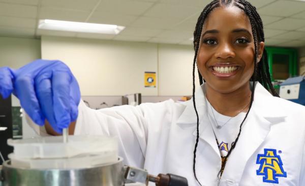 Breyana Robinson poses in a white lab coat inside a laboratory.