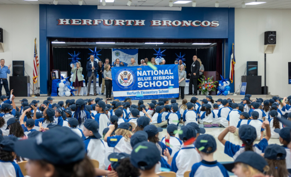 crowd of students and staff stand cheering as banner is displayed