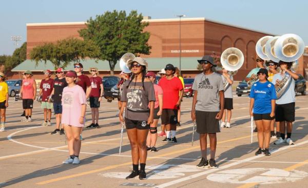 Students stand in marching band formation with instruments