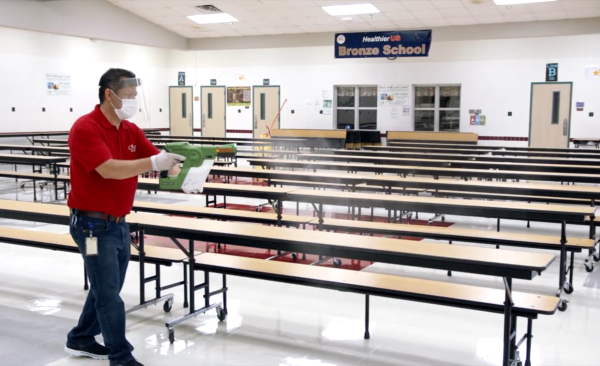 Custodian uses electrostatic disinfecting sprayer in cafeteria