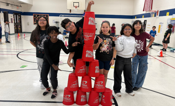 A diverse group of students pose with a tower of stacking cups