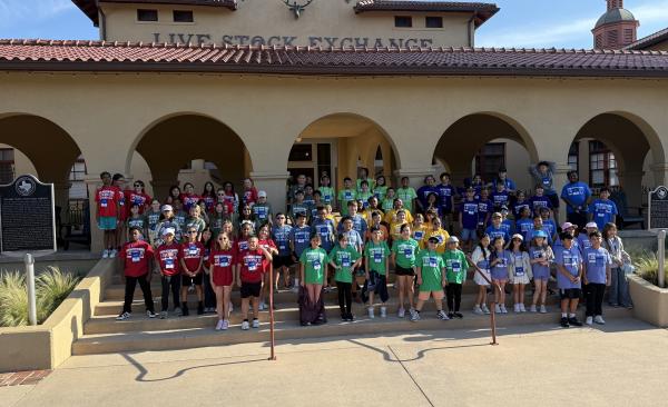 a large group of students stand in front of the Fort Worth Stockyards entrance