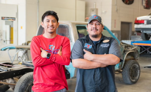 two male teachers stand in front of an vehicle chassis