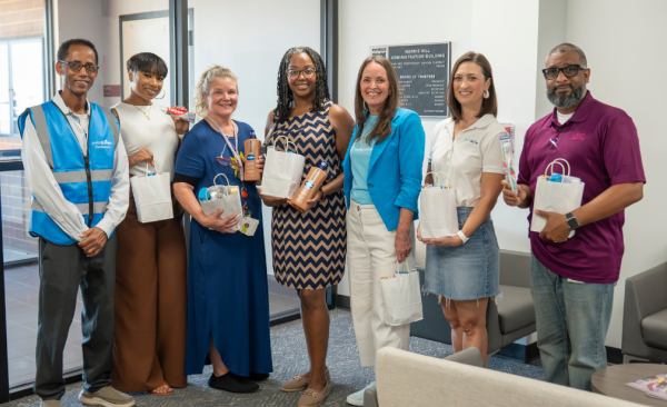 seven adults stand holding white paper bags