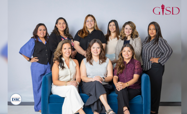a group of adult women sit and stand while smiling straight on at the camera