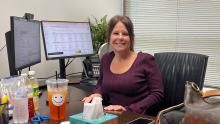 An employee smiles at her desk.