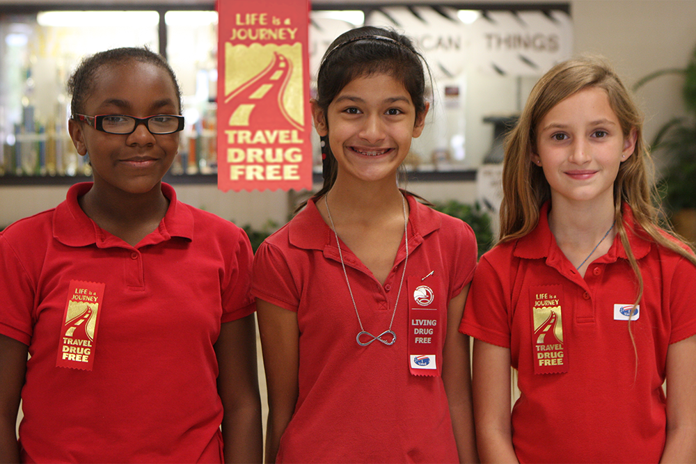 Three girls wearing ribbons in support of red ribbon week.