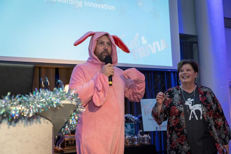 A man in a bunny outfit speaks to the crowd as a woman smiles and looks at him 