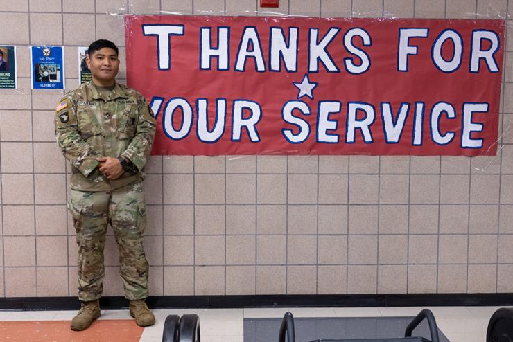 Veteran in uniform standing next to a banner "Thanks for your service"