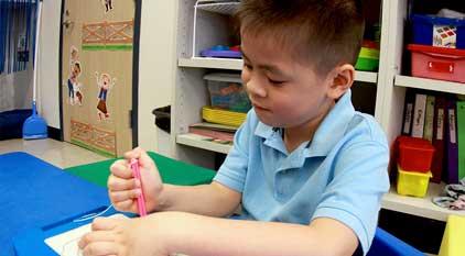 A student with autism drawing in class and wearing blue