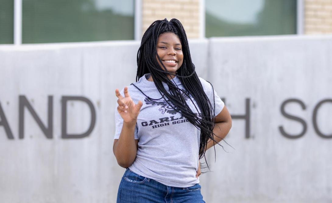 Ivy Veail posing posing in front of GHS while making the school's spirit hand sign.
