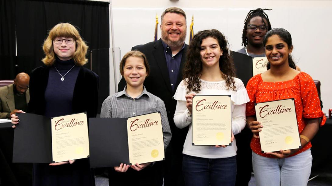 Five students standing with Board President Wes Johhsnon. Each child is holding a certificate