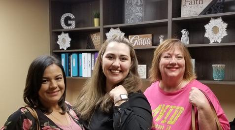 Office staff smiling and posing together with their purses.