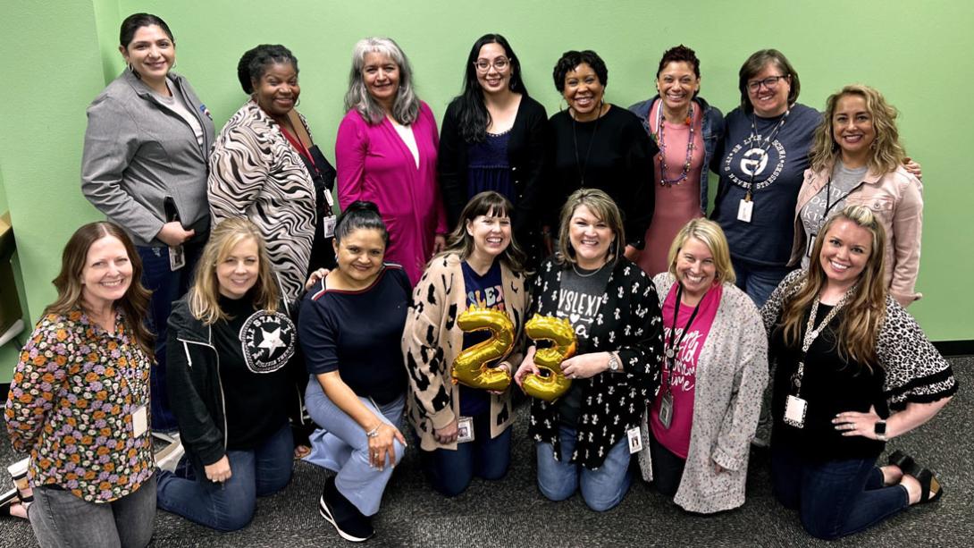 Garland ISD Dyslexia Therapists smile in a room together; some are kneeling, and others are standing.