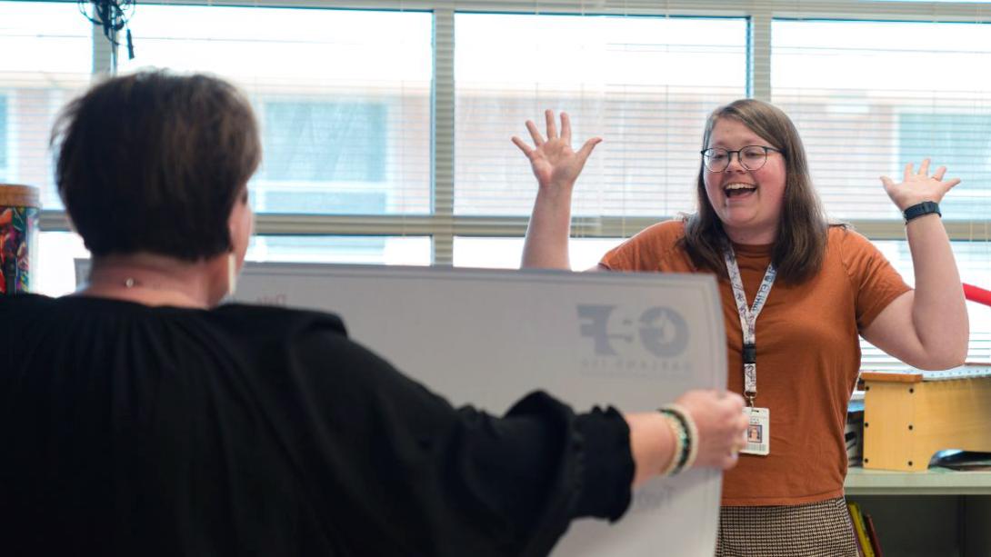 A teacher lifts her hands up in celebration upon seeing her winning grant funds from GEF.