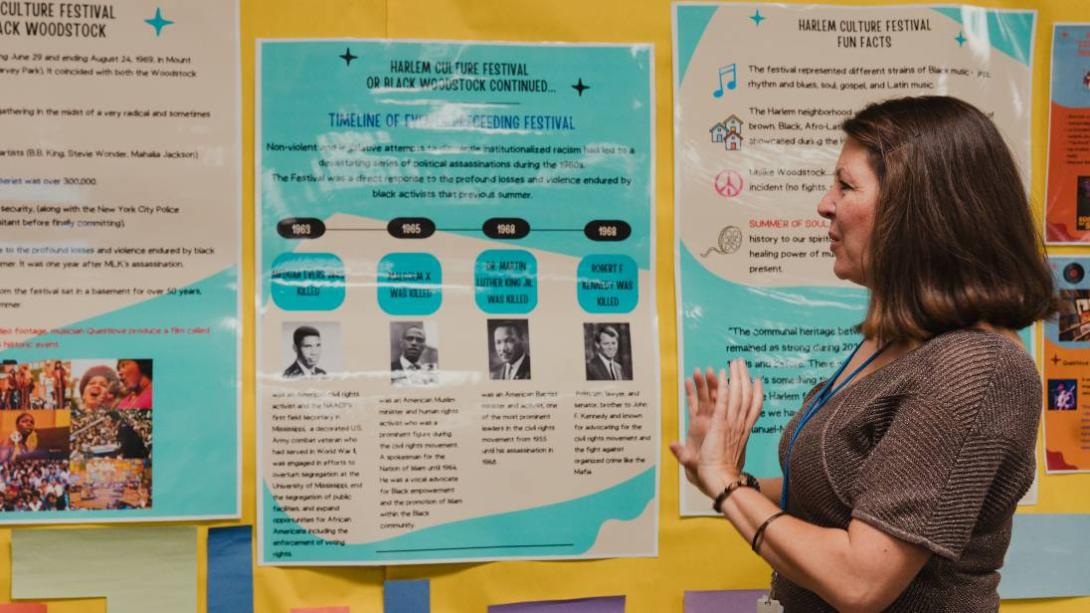South Garland High School Librarian looks at poster in the background.