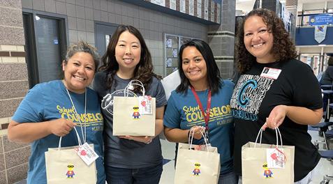 Several school counselors showing off their counseling spirit wear and "thank you" goodie bags for the work they do.