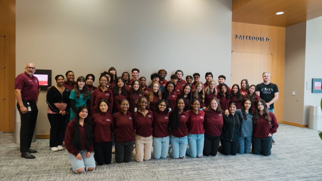 A group of students pose kneeling and standing with the Superintendent.
