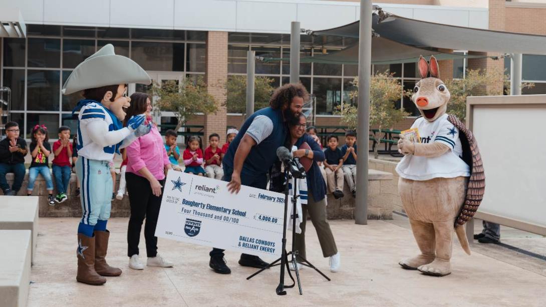 Dallas Cowboys mascot joins group hug with students and their teacher.