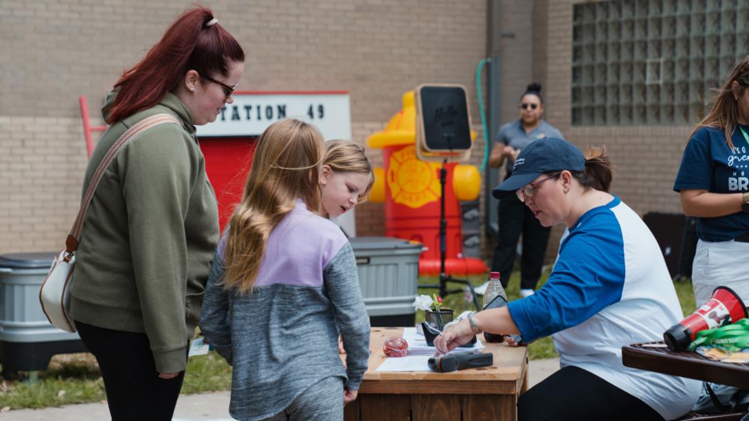 A woman at a desk picks up a packet for a family at the Herfurth PTA Fire Safety Program.