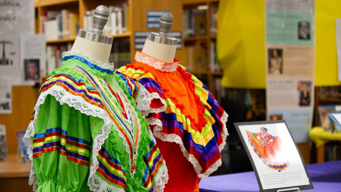 Two colorful Folkloric dresses are displayed, with a sign next to them explaining their history.