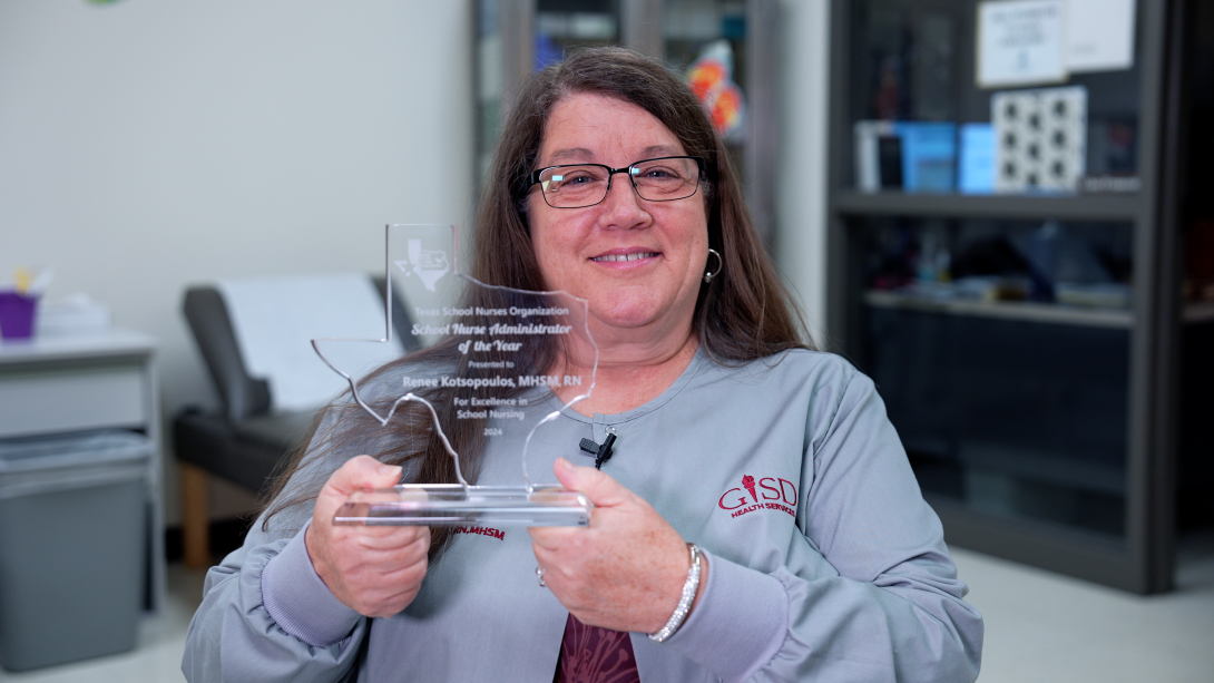 Nurse K smiles while holding a glass Texas-shaped award reading "TSNO School Nurse Administrator of the Year".