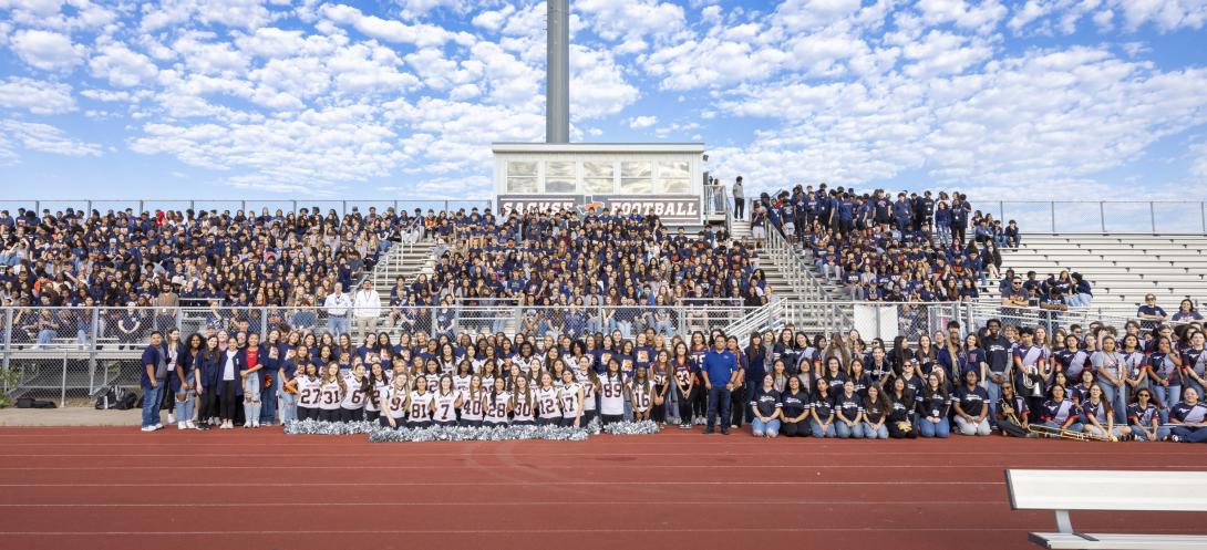 Students fill the bleachers smiling 