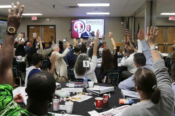 Large group of committee members responding to the speaker, Mr. Selders, with their hands raised.