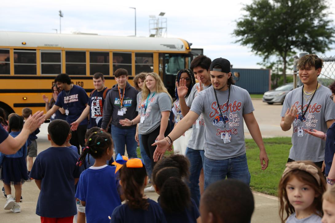 Older students give high fives to younger students as they walk by