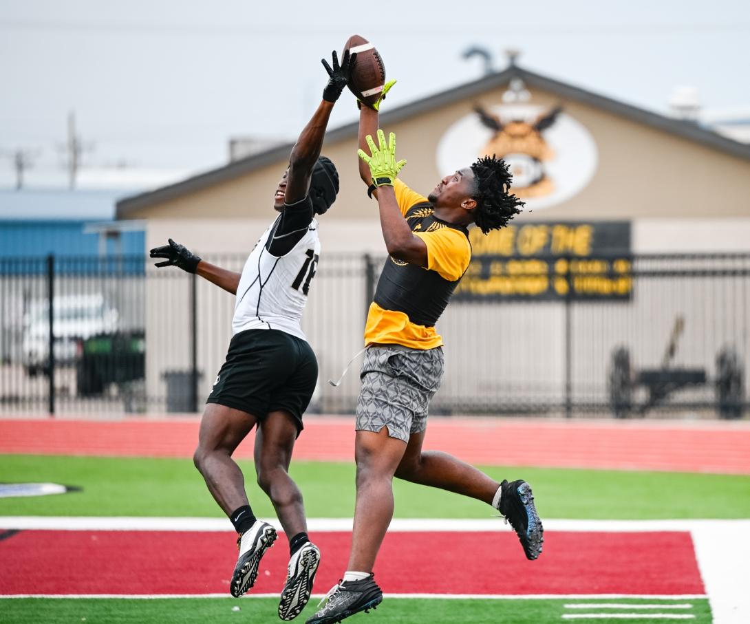 Two football players jump up trying to catch the ball