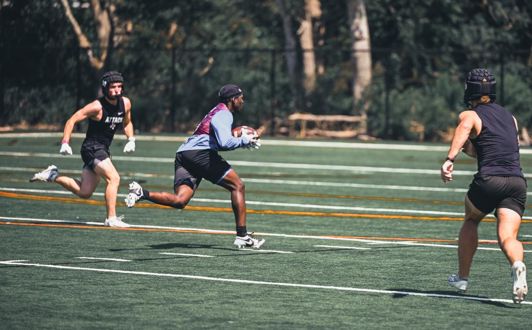 Football players runs between defenders working to catch the ball