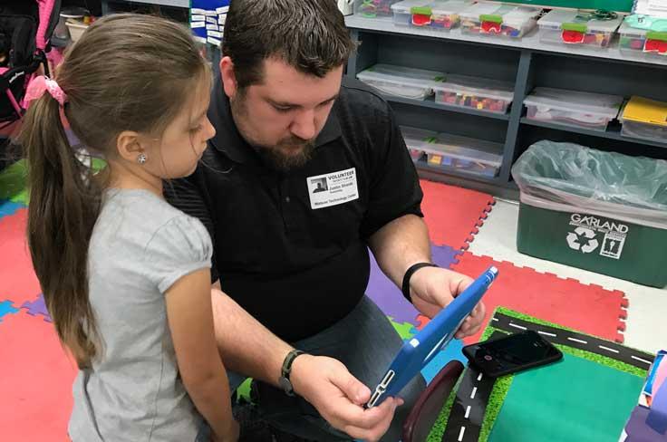 Volunteer helping young student with tablet