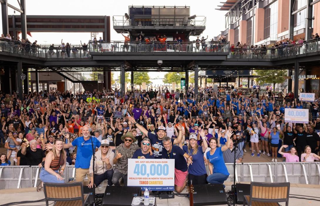 A large crowd of people stand together smiling to the camera