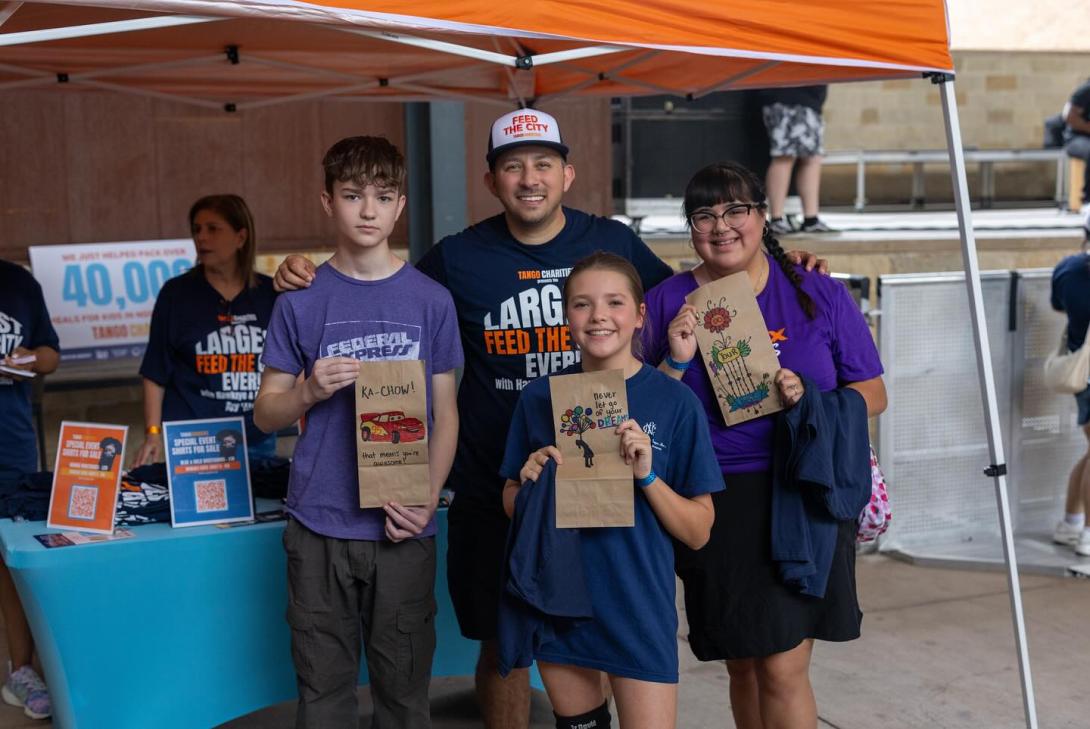 A man stands with three children holding decorated brown lunch bags