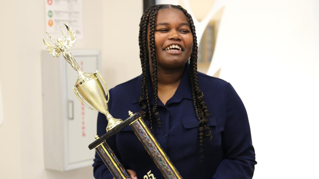 Casey Dozier smiles as she holds her InvestWrite trophy.